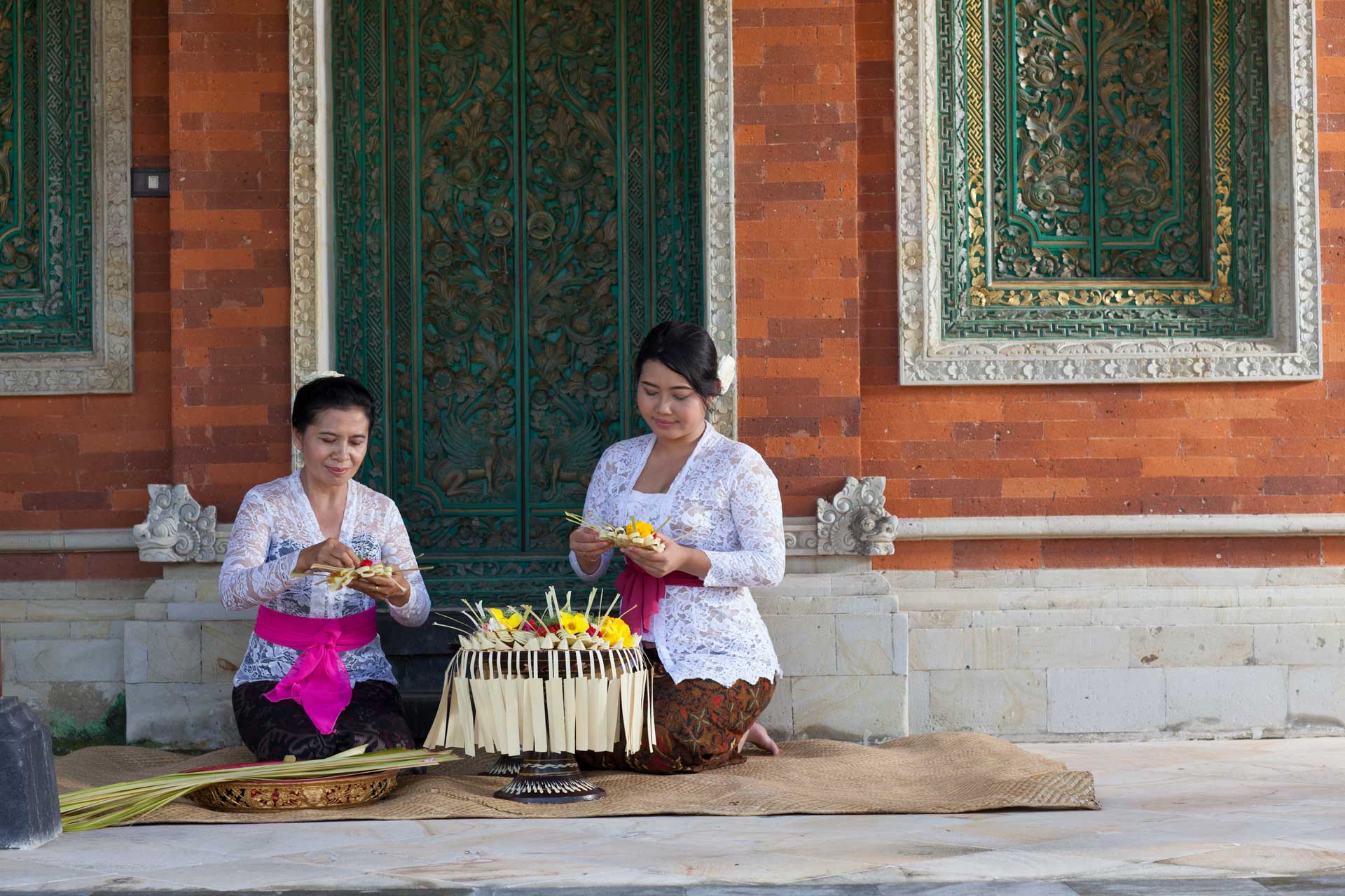 Two Balinese women demonstrating canang making zoomed