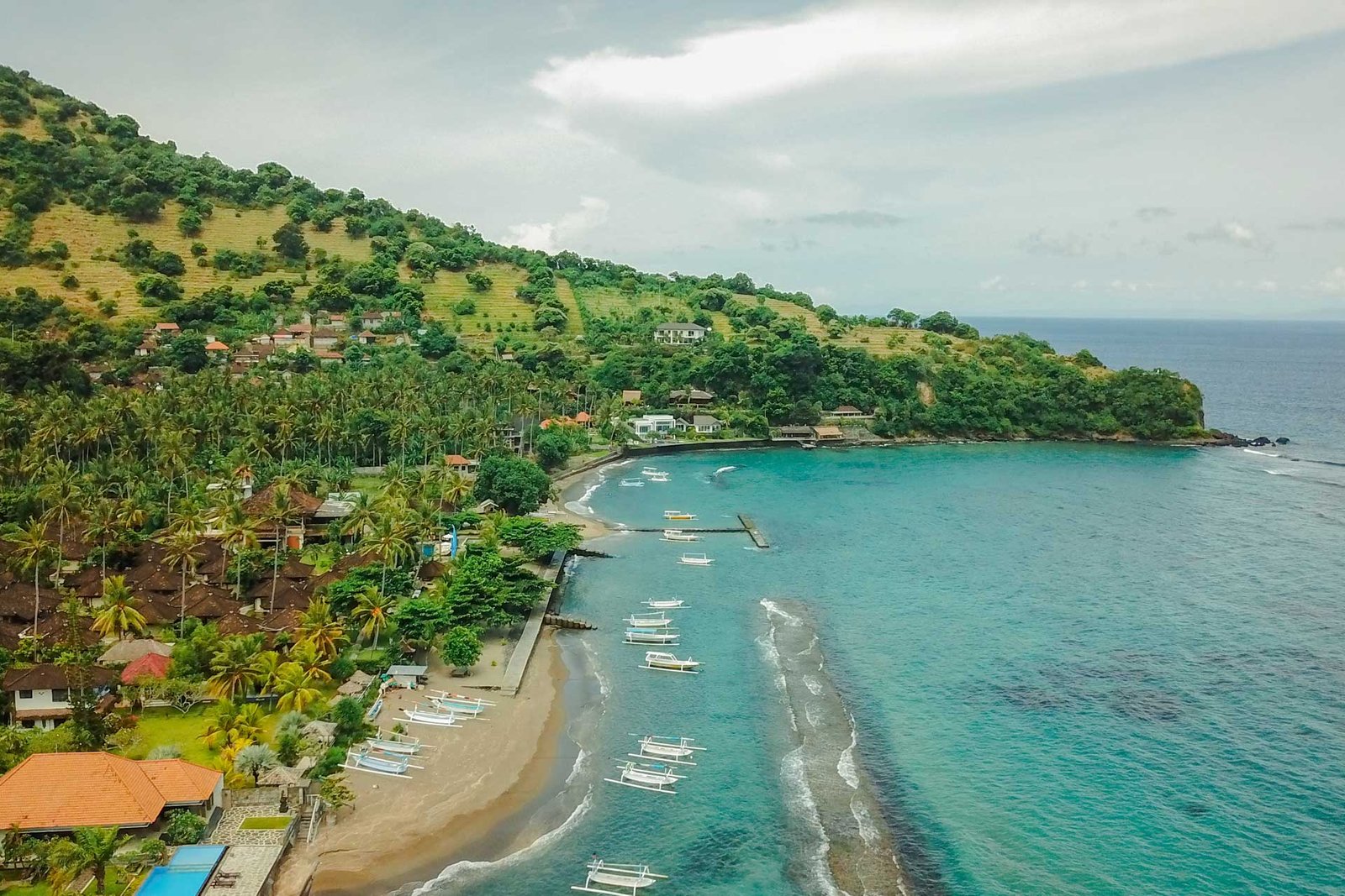 Aerial view of Puri Bagus Candidasa shores with a hill in the background
